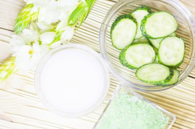 Salatalık ev spa ve saç bakım kavramı. Dilimlenmiş salatalık, yağ, deniz tuzu, banyo havlu şişe. Saman açık renkli. Portre