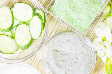 Salatalık ev spa ve saç bakım kavramı. Dilimlenmiş salatalık, yağ, deniz tuzu, banyo havlu şişe. Saman açık renkli. Portre