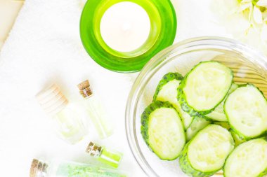 Salatalık ev spa ve saç bakım kavramı. Salatalık, yağ, mum, banyo havlu şişe dilimlenmiş. Saman açık renkli. Portre