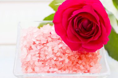 Spa ve sağlıklı yaşam ayarı ile gül çiçek, deniz tuzu, bir şişe ahşap beyaz arka plan üzerinde yağda