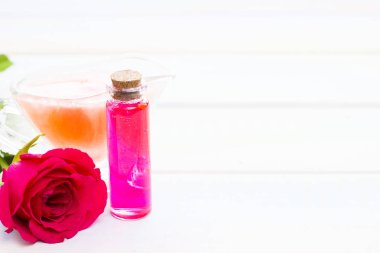 Spa ve sağlıklı yaşam ayarı ile gül çiçek, deniz tuzu, bir şişe ahşap beyaz arka plan üzerinde yağda