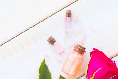 Spa ve sağlıklı yaşam ayarı ile gül çiçek, deniz tuzu, bir şişe ahşap beyaz arka plan üzerinde yağda