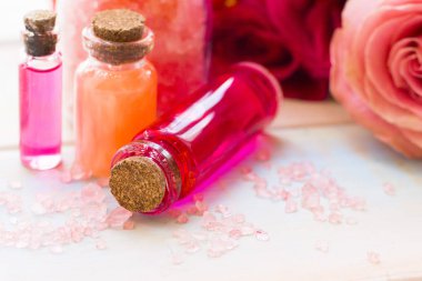 Spa ve sağlıklı yaşam ayarı ile gül çiçek, deniz tuzu, bir şişe ahşap beyaz arka plan üzerinde yağda