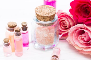 Spa ve sağlıklı yaşam ayarı ile gül çiçek, deniz tuzu, bir şişe ahşap beyaz arka plan üzerinde yağda