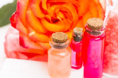 Spa ve sağlıklı yaşam ayarı ile gül çiçek, deniz tuzu, bir şişe ahşap beyaz arka plan üzerinde yağda