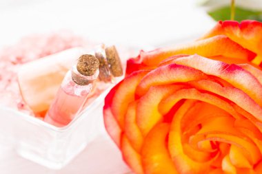 Spa ve sağlıklı yaşam ayarı ile gül çiçek, deniz tuzu, bir şişe ahşap beyaz arka plan üzerinde yağda