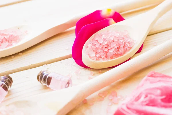 Spa and wellness setting with rose flower, sea salt, oil in a bottle on wooden old background closeup