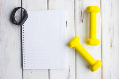 Diyet Zayıflama kilo kaybı kavramı zamanı. Spor, fitness, elma, spor ayakkabıları, şişe su ve sarı ağırlık beyaz ahşap zemin üzerinde