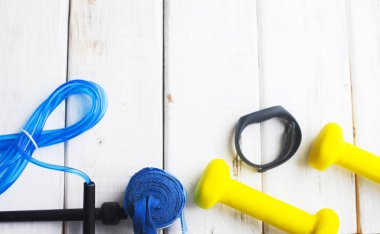 Diyet Zayıflama kilo kaybı kavramı zamanı. Spor, fitness, elma, spor ayakkabıları, şişe su ve sarı ağırlık beyaz ahşap zemin üzerinde