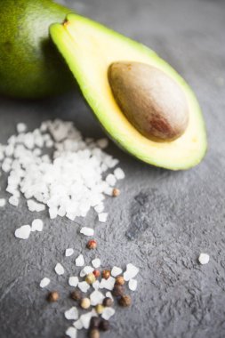 Heathy gıda vejetaryen kavramı. Kopya alanı, üstten görünüm karanlık bir beton zemin üzerine avokado ve tuz taneleri kesmek