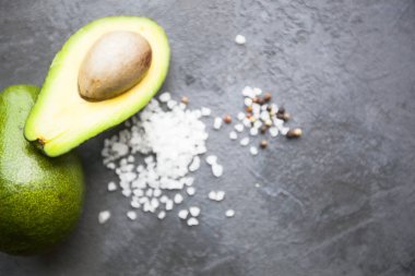 Heathy gıda vejetaryen kavramı. Kopya alanı, üstten görünüm karanlık bir beton zemin üzerine avokado ve tuz taneleri kesmek