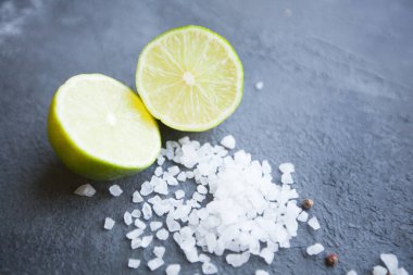 Heathy gıda vejetaryen kavramı. Kopya alanı, üstten görünüm karanlık bir beton zemin üzerine limon ve tuz taneleri kesmek