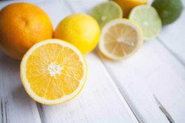 Meyve çayı, kokteyl, tatlı kavramı. Kes ve bütün taze portakal, limon ve limes bir beyaz ahşap tablo