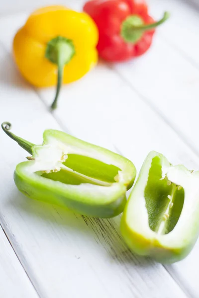 Healthy Food, Vegetarian Concept. A sweet green pepper cut in halves, red and yellow whole peppers on a white wooden background with copy space