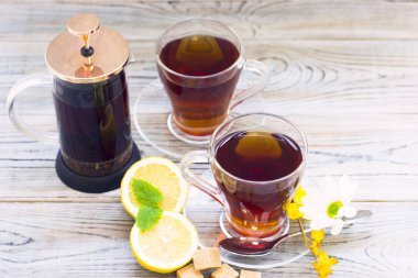 Siyah çay töreni - bardağın dolu çay, cam aranjman, çay yaprakları, şeker, sarı limon, çiçek, baharat ahşap Komiteler arka plan üzerinde. Üstten görünüm