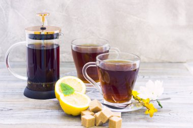 Siyah çay töreni - bardağın dolu çay, cam aranjman, çay yaprakları, şeker, sarı limon, çiçek, baharat ahşap Komiteler arka plan üzerinde. Üstten görünüm