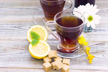 Siyah çay töreni - bardağın dolu çay, cam aranjman, çay yaprakları, şeker, sarı limon, çiçek, baharat ahşap Komiteler arka plan üzerinde. Üstten görünüm