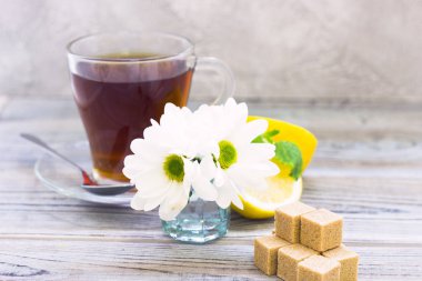 Siyah çay töreni - bardağın dolu çay, cam aranjman, çay yaprakları, şeker, sarı limon, çiçek, baharat ahşap Komiteler arka plan üzerinde. Üstten görünüm