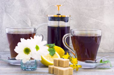 Siyah çay töreni - bardağın dolu çay, cam aranjman, çay yaprakları, şeker, sarı limon, çiçek, baharat ahşap Komiteler arka plan üzerinde. Üstten görünüm