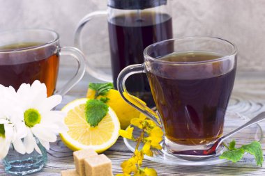 Siyah çay töreni - bardağın dolu çay, cam aranjman, çay yaprakları, şeker, sarı limon, çiçek, baharat ahşap Komiteler arka plan üzerinde. Üstten görünüm