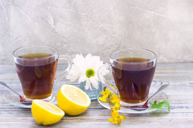 Siyah çay töreni - bardağın dolu çay, cam aranjman, çay yaprakları, şeker, sarı limon, çiçek, baharat ahşap Komiteler arka plan üzerinde. Üstten görünüm