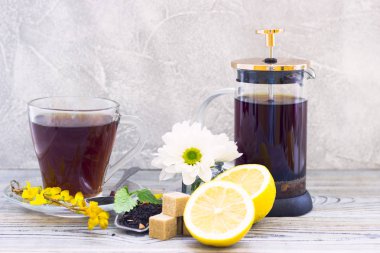 Siyah çay töreni - bardağın dolu çay, cam aranjman, çay yaprakları, şeker, sarı limon, çiçek, baharat ahşap Komiteler arka plan üzerinde. Üstten görünüm