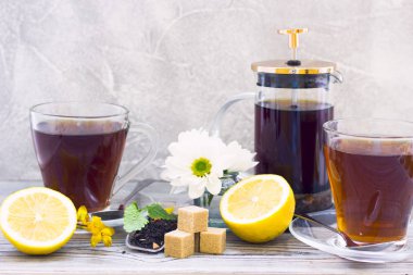 Siyah çay töreni - bardağın dolu çay, cam aranjman, çay yaprakları, şeker, sarı limon, çiçek, baharat ahşap Komiteler arka plan üzerinde. Üstten görünüm