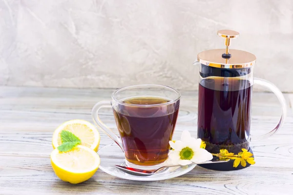 Siyah çay töreni - bardağın dolu çay, cam aranjman, çay yaprakları, şeker, sarı limon, çiçek, baharat ahşap Komiteler arka plan üzerinde. Üstten görünüm