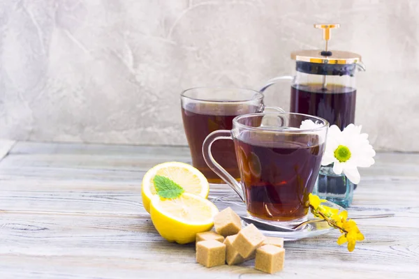 Siyah çay töreni - bardağın dolu çay, cam aranjman, çay yaprakları, şeker, sarı limon, çiçek, baharat ahşap Komiteler arka plan üzerinde. Üstten görünüm