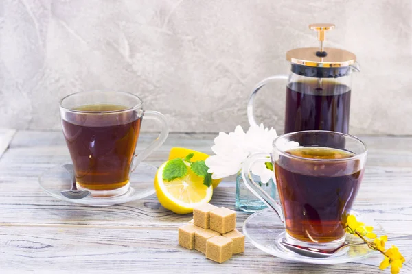 Siyah çay töreni - bardağın dolu çay, cam aranjman, çay yaprakları, şeker, sarı limon, çiçek, baharat ahşap Komiteler arka plan üzerinde. Üstten görünüm