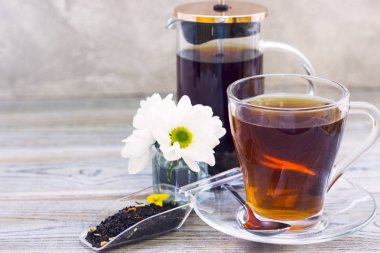 Siyah çay töreni - bardağın dolu çay, cam aranjman, çay yaprakları, şeker, sarı limon, çiçek, baharat ahşap Komiteler arka plan üzerinde. Üstten görünüm