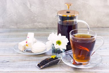 Siyah çay töreni - bardağın dolu çay, cam aranjman, çay yaprakları, şeker, sarı limon, çiçek, baharat ahşap Komiteler arka plan üzerinde. Üstten görünüm