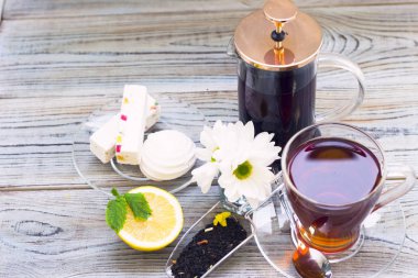 Siyah çay töreni - bardağın dolu çay, cam aranjman, çay yaprakları, şeker, sarı limon, çiçek, baharat ahşap Komiteler arka plan üzerinde. Üstten görünüm