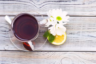 Siyah çay töreni - bardağın dolu çay, cam aranjman, çay yaprakları, şeker, sarı limon, çiçek, baharat ahşap Komiteler arka plan üzerinde. Üstten görünüm