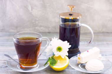 Siyah çay töreni - bardağın dolu çay, cam aranjman, çay yaprakları, şeker, sarı limon, çiçek, baharat ahşap Komiteler arka plan üzerinde. Üstten görünüm