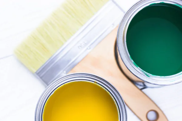 House renovation concept, colorfull paint cans and paintbrushes on wooden background top view