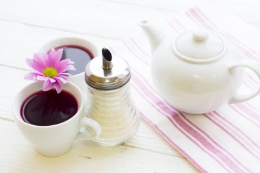 Siyah çay töreni - bir fincan çay, çaydanlık, şeker, kek, çiçekleri Beyaz ahşap rustik arka planda