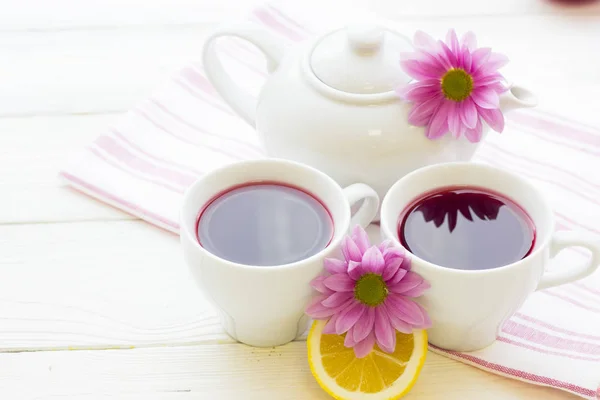 Schwarze Teezeremonie - eine Tasse Tee, Teekanne, Zucker, Kuchen, Blumen auf weißem Holz rustikalem Hintergrund — Stockfoto