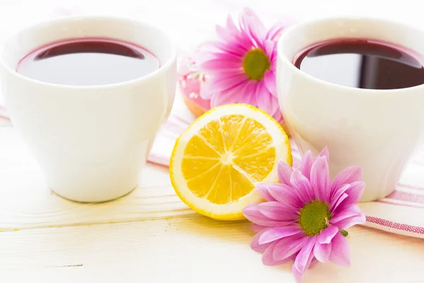 Zwarte theeceremonie - een kopje thee, theepot, suiker, gebak, bloemen op witte houten rustieke achtergrond — Stockfoto