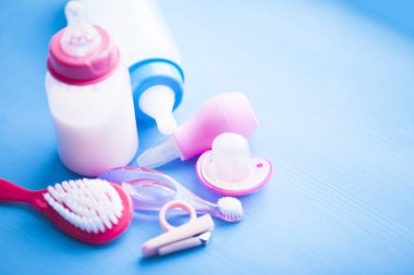 Yeni doğmuş bebek hikayesi. Çocuk oyuncakları, makas, bebek şişesi, meme ucu, mavi arka plan üzerinde saç fırçası