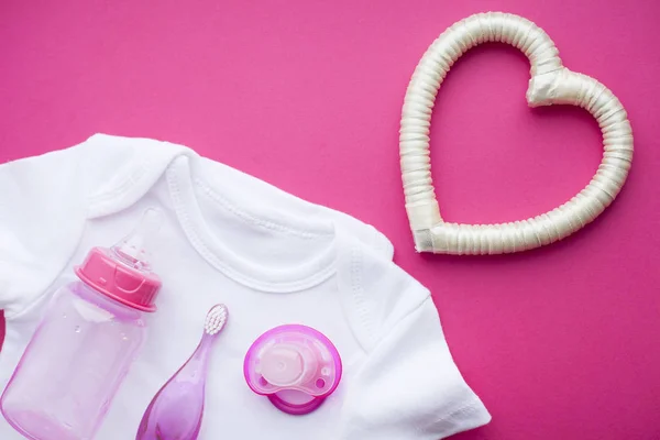 Pasgeboren baby verhaal. T-shirt en kinderspeelgoed, schaar, baby fles, tepel, haarborstel op rode achtergrond — Stockfoto