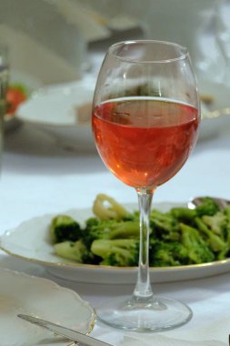 Bir bardak brokoli salata yanındaki bir masada pembe şarap. Dikey resim.