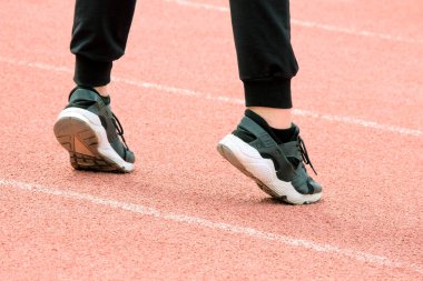 s beyaz dış taban üzerinde parmaklarını spor zemin üzerinde durdu. Fitness dersleri veya stadyumda çalıştırmadan önce ısınma. Siyah spor ayakkabı zekâ arka görünümü bir kız.