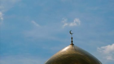 Altın bir minare Islam - mavi gökyüzü bulutlu güneş ışığı parlama ile Hilal sembolü ile. Timelapse.
