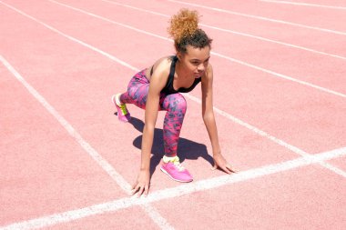 Yaşam tarzı. Güzel, Genç bir Afro-Amerikan Kız sportif siyah T-shirt ve pembe spor ayakkabı koşu bandı başlangıç Şerit üzerindeki yarış hazırlanıyor. Kopya alanı.