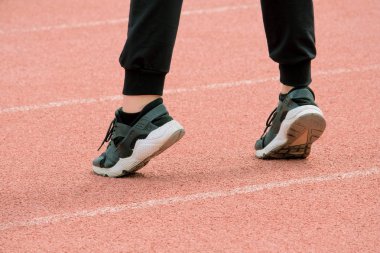 Siyah spor ayakkabı, Pantolon kadın bacaklar çorap beyaz çizgili pembe koşu bandı arka plan üzerinde durmak. Kız fitness devreye girer.