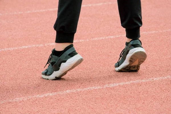 Siyah spor ayakkabı, Pantolon kadın bacaklar çorap beyaz çizgili pembe koşu bandı arka plan üzerinde durmak. Kız fitness devreye girer.