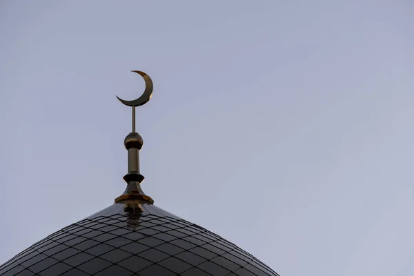 The symbol of Islam is a golden crescent moon. The top of the mosque minaret. Blue evening or morning sky.