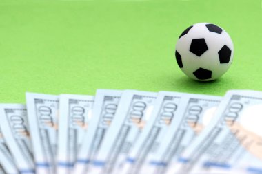Yüz dolarlık banknot ABD'nin yanında yeşil bir alanda bir futbol topu. Kavram para futbol, fanlar, oyuncu ve antrenörler, maaş kar bahis spor. Sığ derinlik-in tarla.