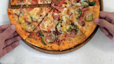 İki el al adet sosis, sebze, peynir, pasta hamur içinde baharatlar. Yakın pizza ahşap plaka üzerinde çekim.